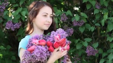 Güzel gülümseyen genç kadın elinde Açık Eflatun çiçek buketi ile