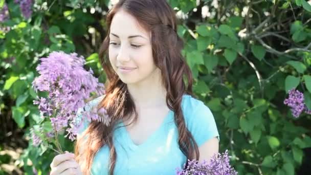Hermosa joven sonriente con flores lila ramo en las manos al aire libre — Vídeos de Stock