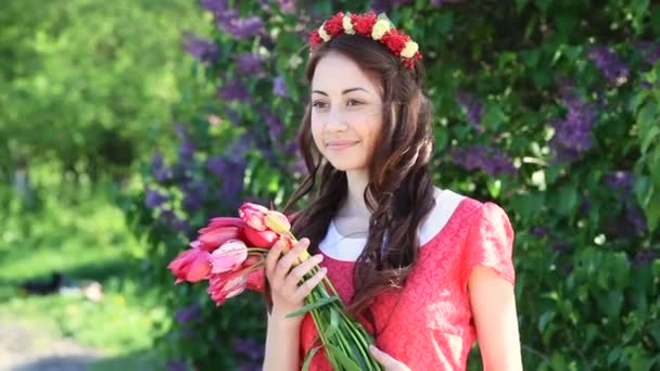 Jonge vrouw met een boeket van tulpen in het park in het voorjaar — Stockvideo