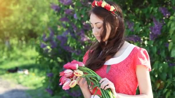 Молода жінка з букетом тюльпанів у парку навесні — стокове відео