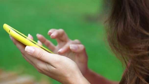 Cerrar la mano de la mujer con el teléfono inteligente y tocar en un parque de pantalla en blanco al aire libre — Vídeos de Stock