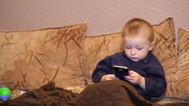 Niño juega juego en un teléfono inteligente — Vídeo de stock