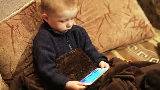 Маленький мальчик смотрит мультик в помещении смартфона — стоковое видео