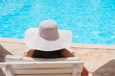 Beyaz şapkalı bir tembel Yüzme Havuz kenarında yatan kadın
