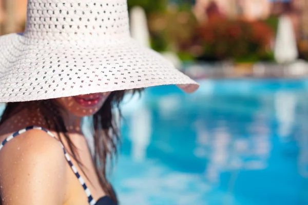 Mooie vrouw in witte grote hoed in de buurt van zwembad op een zonnige dag — Stockfoto