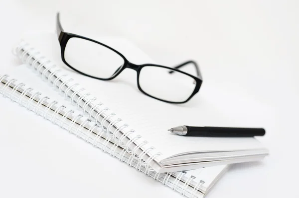 Black pen and glasses lying on notebook close up — Stock Photo, Image