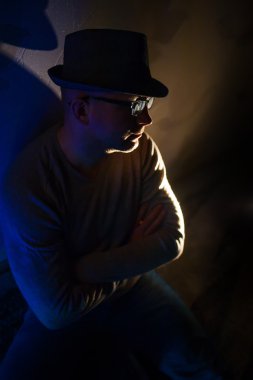adam gözlük ve karanlıkta oturmuş bir şapka