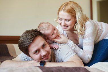 Annem ve babam yatakta bebek oğluyla oynamaya. Mutlu aile kavramı