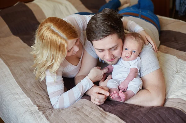 Mama i tata gra z jego synka na łóżku. Szczęśliwa rodzina koncepcja — Zdjęcie stockowe