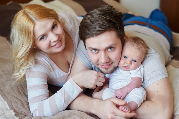 ママとパパがベッドに彼の赤ちゃんの息子と遊ぶ。幸せな家族の概念 — ストック写真