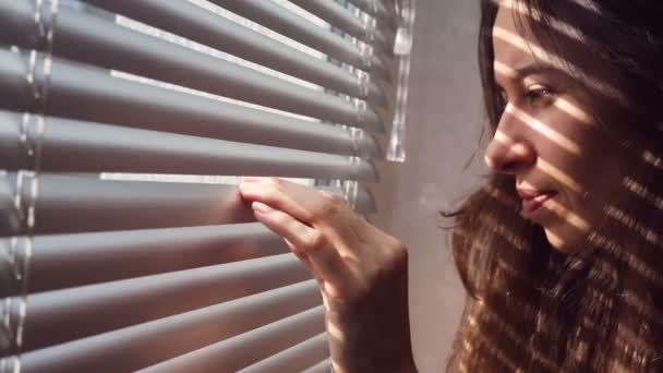 Woman hand pushing the blinds and looking out window — Stock Video