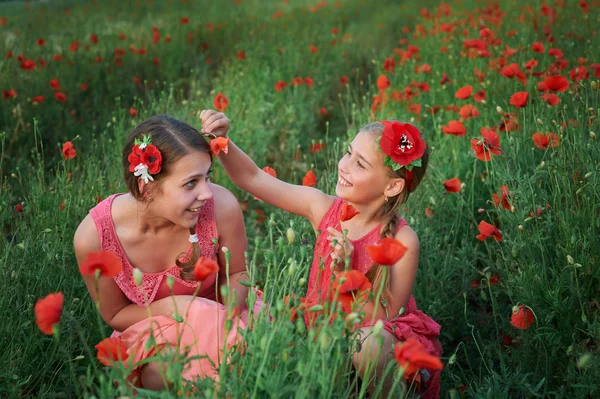 Dos chicas en vestido rojo caminando en el campo de amapola — Foto de Stock