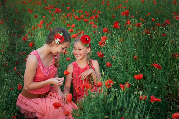 Dos chicas en vestido rojo caminando en el campo de amapola — Foto de Stock