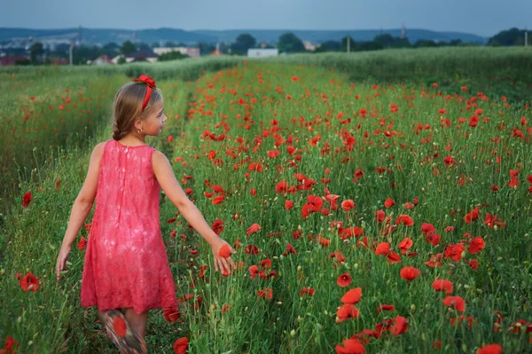 Милая девушка в красном платье гуляет на маковом поле — стоковое фото