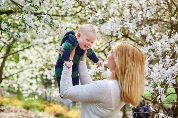 Liten pojke med sin unga mor i den blommande vår trädgården — Stockfoto