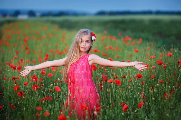 Krásná dívka v červených šatech chodí na makovém poli — Stock fotografie