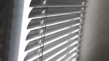 Pencereden gelen güneş ışığı Venedik panjurlarından geliyor.