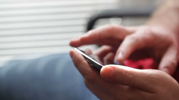 Primer plano de un hombre de negocios mano usando el teléfono celular cerca de la ventana — Vídeos de Stock