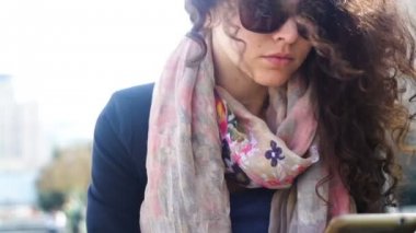 Açık havada smartphone kullanarak güneş gözlüklü genç kadın