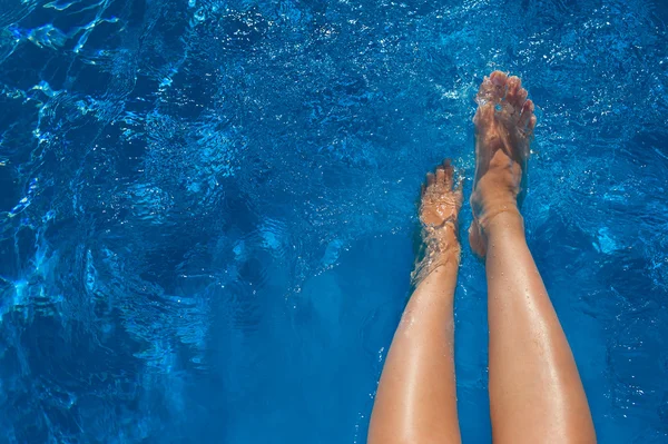 De benen van de vrouw in blauw water zwembad — Stockfoto