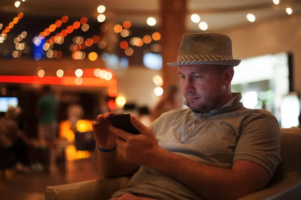 people and technology concept - happy man with smartphone reading message at bar or pub