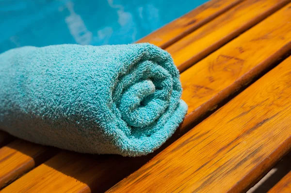Toalla turquesa en una tumbona junto a la piscina azul — Foto de Stock