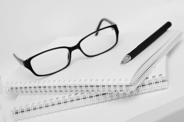 Очки и ручка на белом блокноте в клетке — стоковое фото
