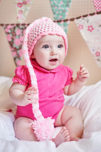 Newborn baby girl in pink knitted hat on the bed — Stock Photo, Image