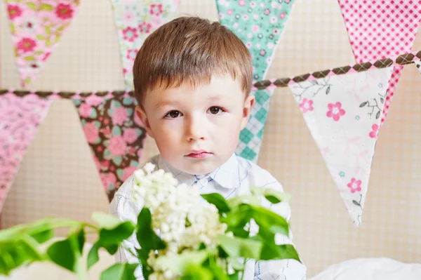 Kleiner Junge mit bunten Fahnen auf dem Hintergrund — Stockfoto