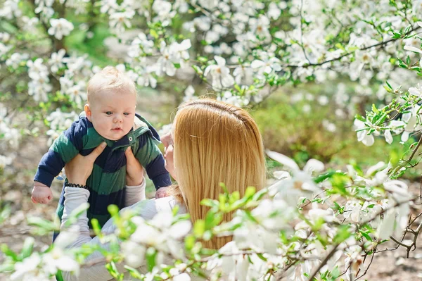 Menino com mãe jovem no jardim de flores de primavera — Fotografia de Stock