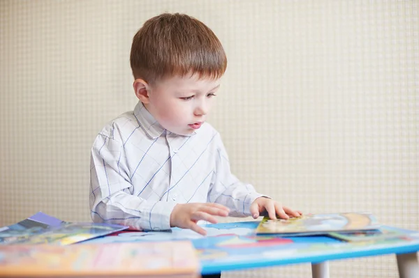 小男孩坐在桌子和读的书 — 图库照片