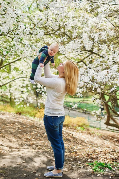 Little baby boy with young mother in the spring blossom garden — Stock Photo, Image