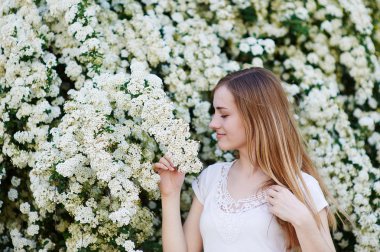beyaz çiçekli ağaçlar yakınındaki parkta yürüyen güzel kadın