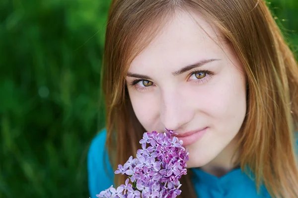 Vacker kvinna med blommor i lila i händerna — Stockfoto