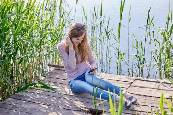 Bella donna seduta sul molo di legno il fiume — Foto Stock