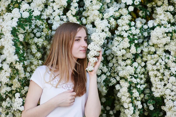 Hermosa mujer caminando en el parque cerca de los árboles de flores blancas —  Fotos de Stock