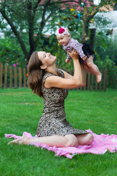 Conceito de criança e paternidade - mãe feliz com pequeno bebê sentado em cobertor no parque — Fotografia de Stock