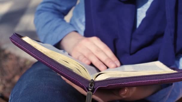 Крупный план женских рук во время чтения Библии снаружи — стоковое видео