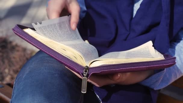 Close-up of womans hands while reading the Bible outside — Stock Video