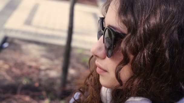Красивая молодая женщина в солнечных очках, смотрящая вперед — стоковое видео