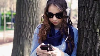 güzel genç kadın güneş gözlüğü parkta kulaklık ile müzik dinlemek