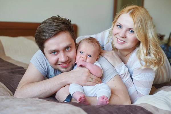 美しい幸せなカップルと彼らの赤ちゃんが一緒にベッドでリラックス — ストック写真