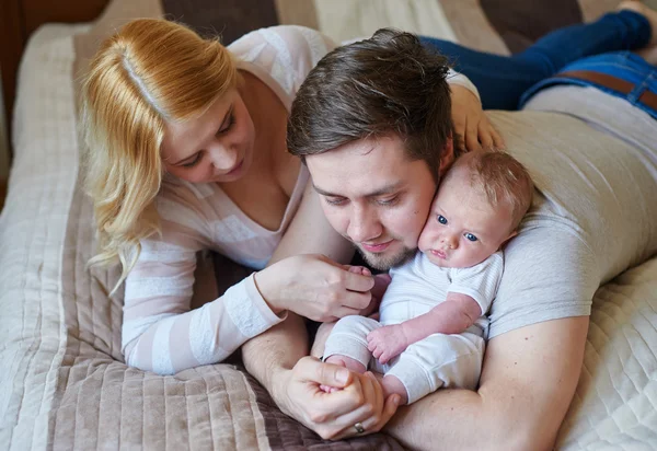 美しい幸せなカップルと彼らの赤ちゃんが一緒にベッドでリラックス — ストック写真