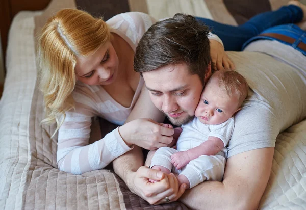 Bella coppia felice e il loro bambino rilassarsi in un letto insieme — Foto Stock