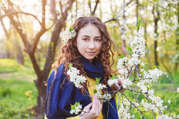 Bela jovem mulher andando em um jardim de primavera florescente — Fotografia de Stock