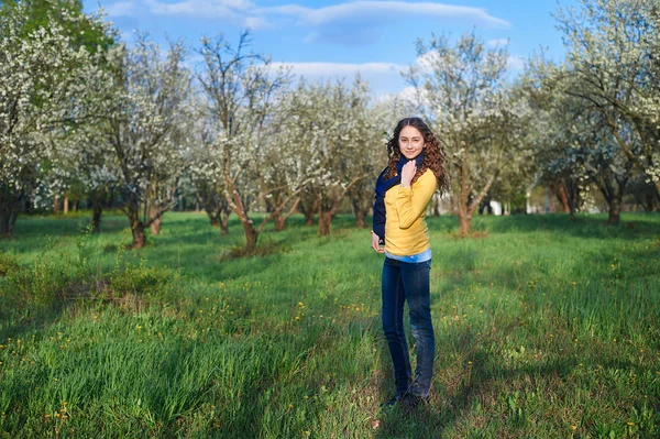 Schöne junge Frau, die in einem blühenden Frühlingsgarten spaziert — Stockfoto