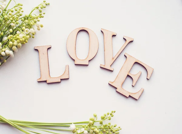 Houten woord liefde en bloemen op witte achtergrond — Stockfoto