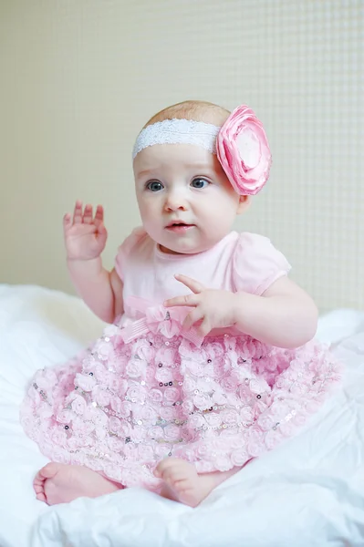 Dziewczyna Słodkie piękne dziecko siedzi na łóżku w różowej sukience — Zdjęcie stockowe