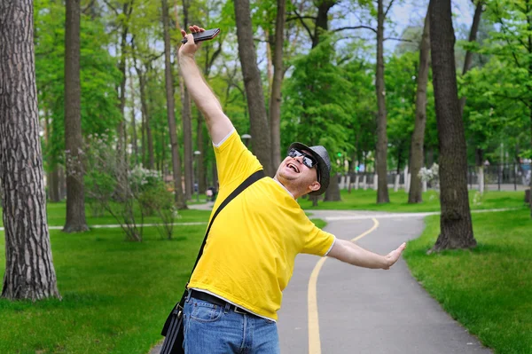 Glücklicher Mann mit Hut und gelbem T-Shirt spaziert durch den Park — Stockfoto