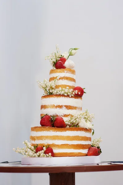 Three-tiered wedding cake with strawberries on table — Stock Photo, Image